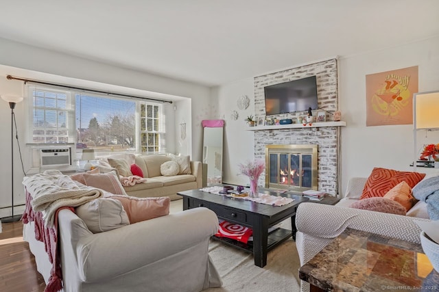 living room with hardwood / wood-style flooring, cooling unit, a large fireplace, and a baseboard radiator