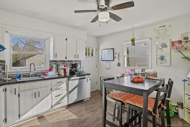 kitchen featuring dishwasher, white cabinets, sink, light wood-type flooring, and tasteful backsplash