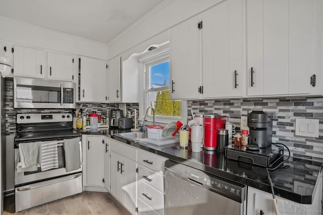 kitchen featuring backsplash, ornamental molding, stainless steel appliances, sink, and white cabinets