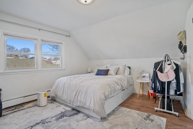 bedroom with light hardwood / wood-style floors, vaulted ceiling, and a baseboard radiator