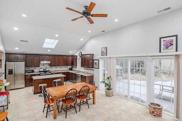 tiled dining room with vaulted ceiling with skylight and ceiling fan