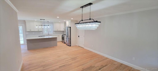 kitchen featuring appliances with stainless steel finishes, backsplash, decorative light fixtures, white cabinets, and a center island