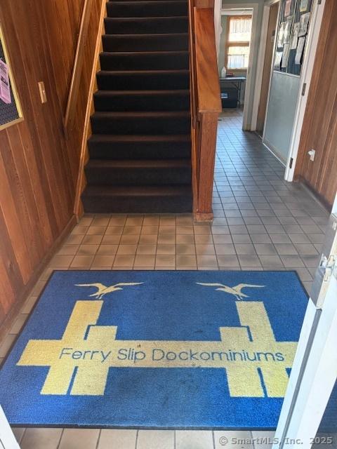 stairway with tile patterned floors and wood walls