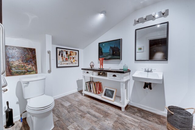 bathroom with hardwood / wood-style flooring, lofted ceiling, and toilet