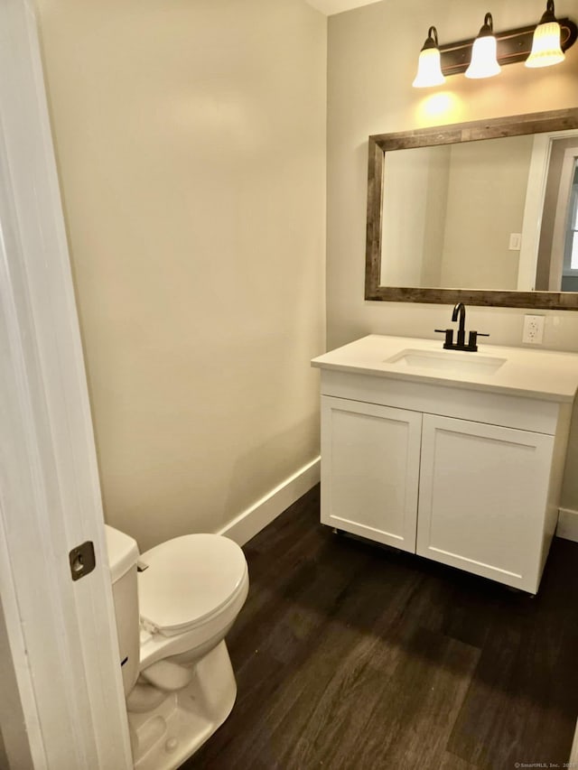 bathroom featuring toilet, hardwood / wood-style flooring, and vanity