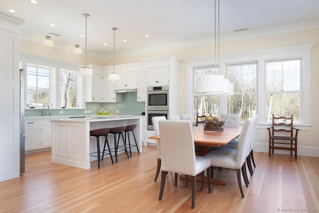 dining area featuring light hardwood / wood-style flooring, ornamental molding, and sink