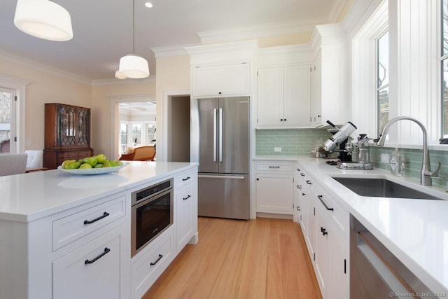 kitchen with white cabinetry, sink, hanging light fixtures, and appliances with stainless steel finishes