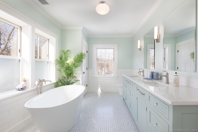 bathroom with vanity, a tub to relax in, ornamental molding, and tile walls