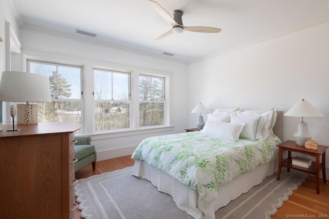 bedroom with multiple windows, ceiling fan, crown molding, and light wood-type flooring