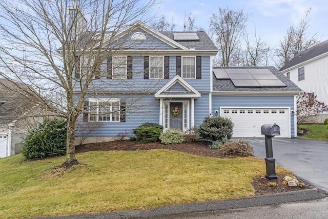 view of front facade featuring a front lawn, a garage, and solar panels