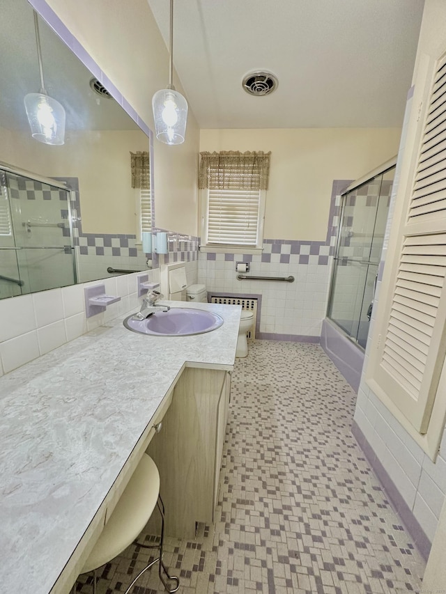 full bathroom with enclosed tub / shower combo, vanity, tile walls, and toilet