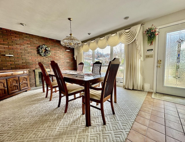 dining room featuring a baseboard heating unit, light tile patterned floors, a chandelier, and brick wall