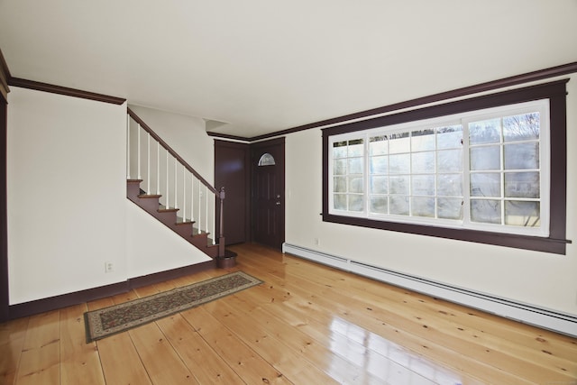 foyer featuring wood-type flooring, a baseboard radiator, crown molding, and a healthy amount of sunlight