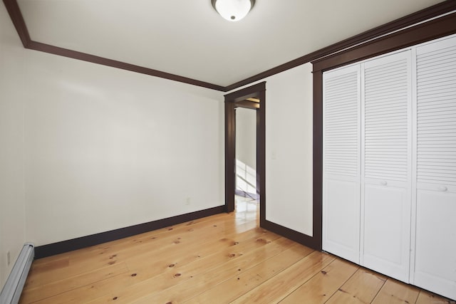 unfurnished bedroom featuring baseboard heating, crown molding, and a closet