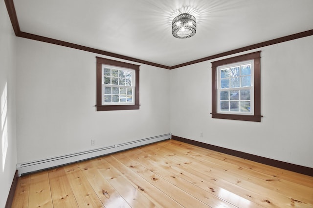 spare room with ornamental molding, light hardwood / wood-style flooring, baseboard heating, and a healthy amount of sunlight