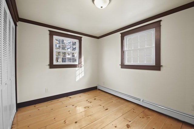 spare room with a baseboard radiator, light hardwood / wood-style flooring, and crown molding