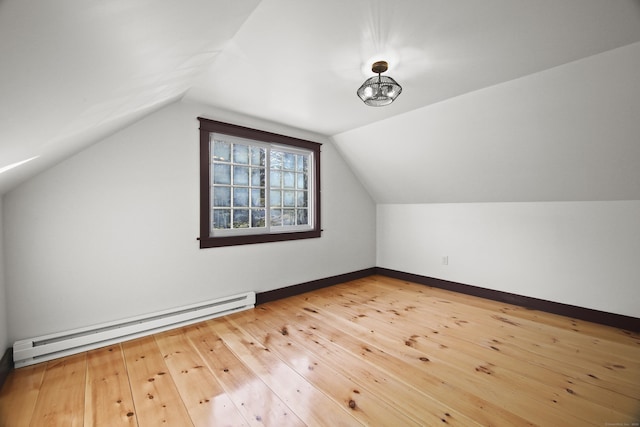 additional living space with wood-type flooring, vaulted ceiling, and a baseboard heating unit