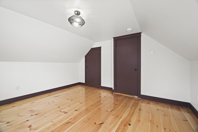 additional living space featuring vaulted ceiling and light wood-type flooring