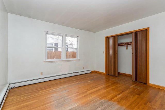 unfurnished bedroom featuring a closet, light hardwood / wood-style flooring, and a baseboard heating unit