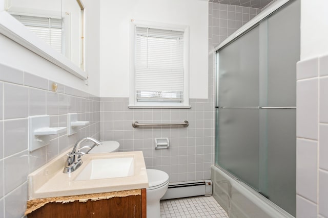 full bathroom with a baseboard heating unit, tile patterned floors, bath / shower combo with glass door, vanity, and tile walls