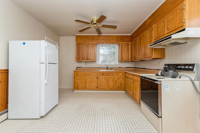 kitchen with ceiling fan, sink, baseboard heating, white appliances, and decorative backsplash