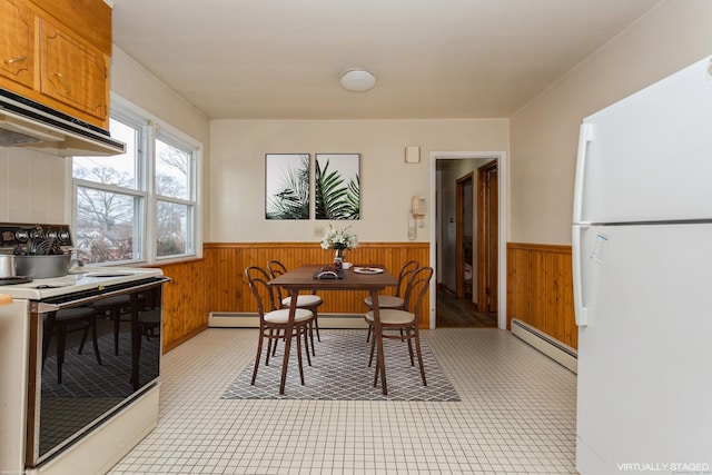 dining space with baseboard heating and wood walls