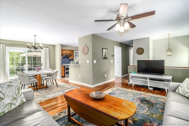 living room featuring wood-type flooring and ceiling fan with notable chandelier