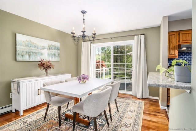 dining room with a baseboard heating unit, a notable chandelier, and light wood-type flooring