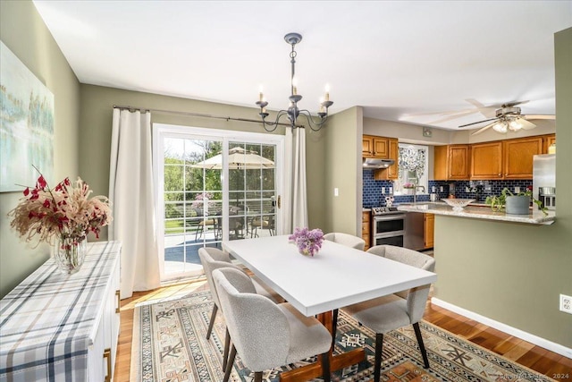 dining room featuring ceiling fan with notable chandelier and light wood-type flooring