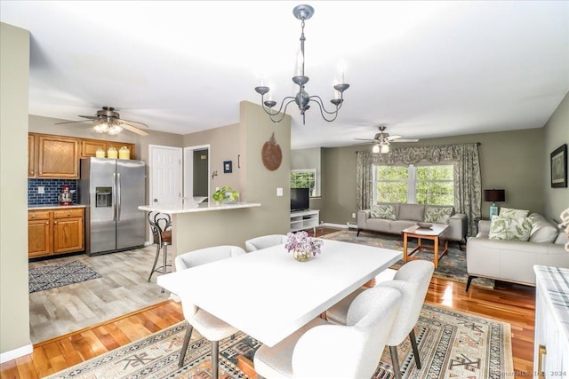 dining area featuring ceiling fan with notable chandelier and light wood-type flooring