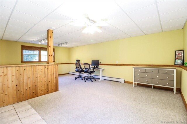 office with a paneled ceiling, rail lighting, wooden walls, ceiling fan, and baseboard heating