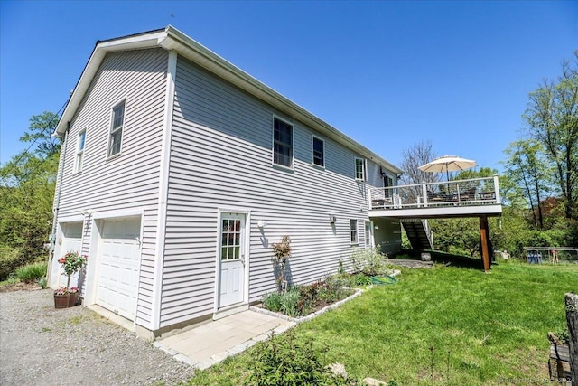 back of property with a lawn, a wooden deck, and a garage