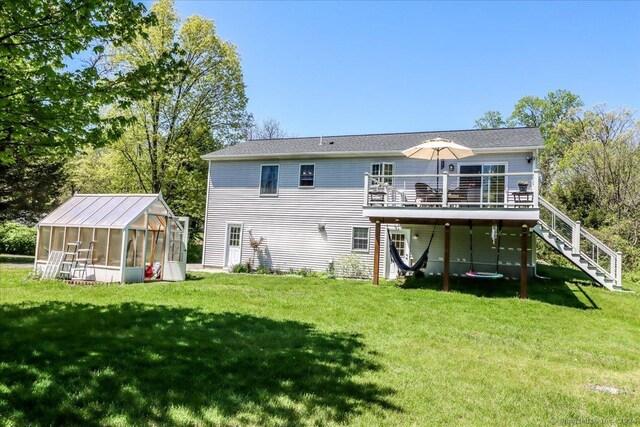 rear view of house with a lawn, an outdoor structure, and a deck