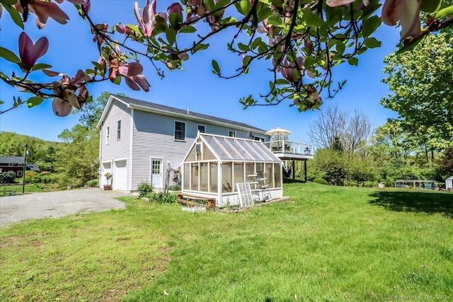 rear view of property featuring a lawn, a sunroom, and a garage