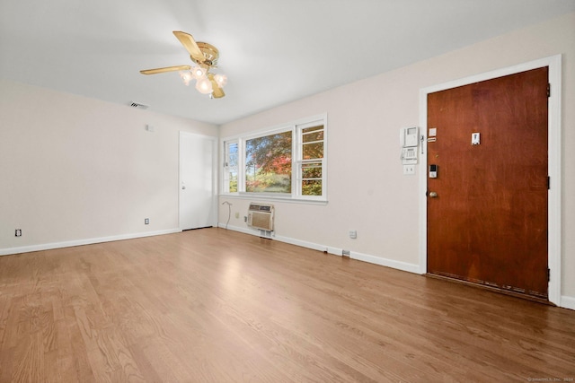 spare room featuring an AC wall unit, ceiling fan, and hardwood / wood-style flooring