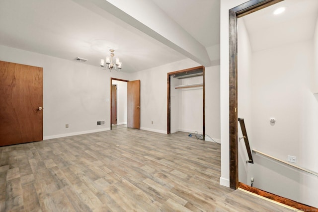 unfurnished bedroom with an inviting chandelier, light hardwood / wood-style flooring, and a closet