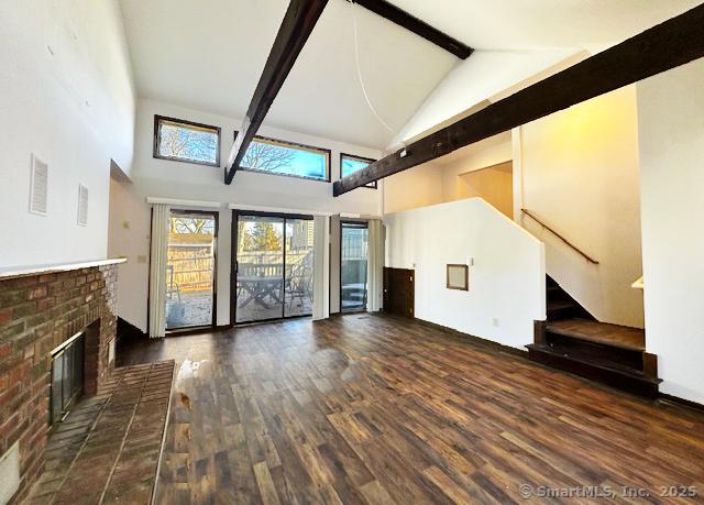 unfurnished living room featuring beamed ceiling, high vaulted ceiling, a brick fireplace, and dark hardwood / wood-style floors