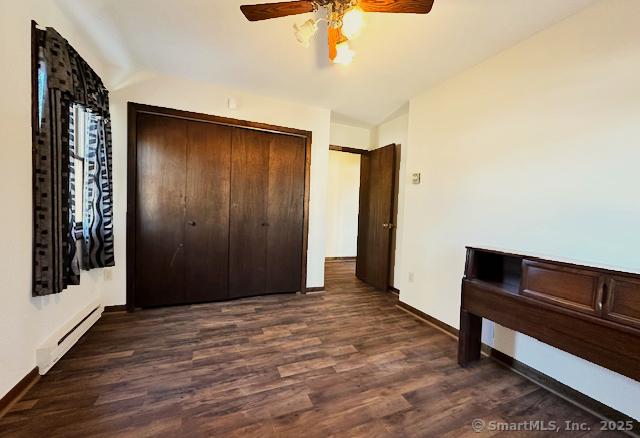 bedroom featuring lofted ceiling, dark wood-type flooring, ceiling fan, a baseboard radiator, and a closet