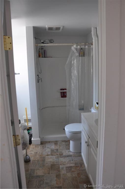 bathroom with curtained shower, vanity, and toilet