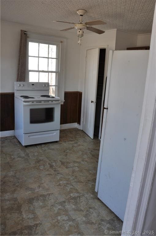 kitchen featuring white appliances, ceiling fan, and wooden walls