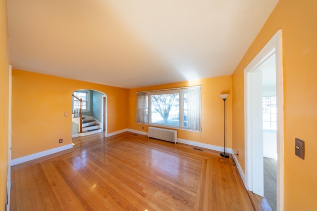 spare room featuring radiator heating unit and hardwood / wood-style floors