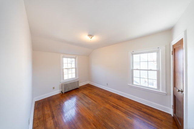 empty room featuring dark hardwood / wood-style flooring, a wealth of natural light, radiator heating unit, and lofted ceiling