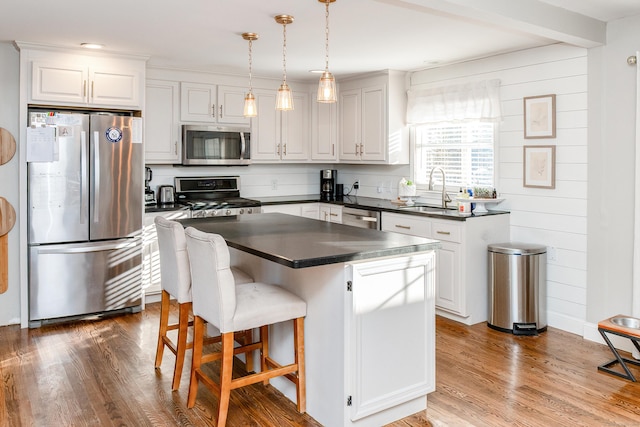 kitchen with pendant lighting, white cabinetry, sink, a center island, and stainless steel appliances