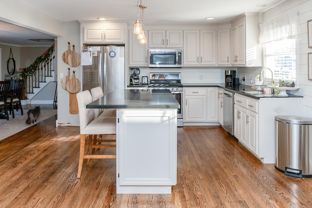 kitchen featuring decorative light fixtures, a breakfast bar area, white cabinets, a center island, and stainless steel appliances