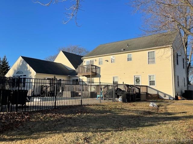 back of property with a balcony and a lawn