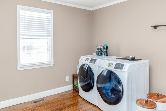 laundry room featuring crown molding, separate washer and dryer, and hardwood / wood-style floors