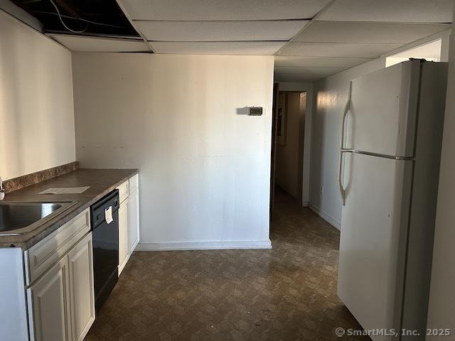 kitchen featuring dishwasher, a drop ceiling, white cabinets, sink, and white fridge