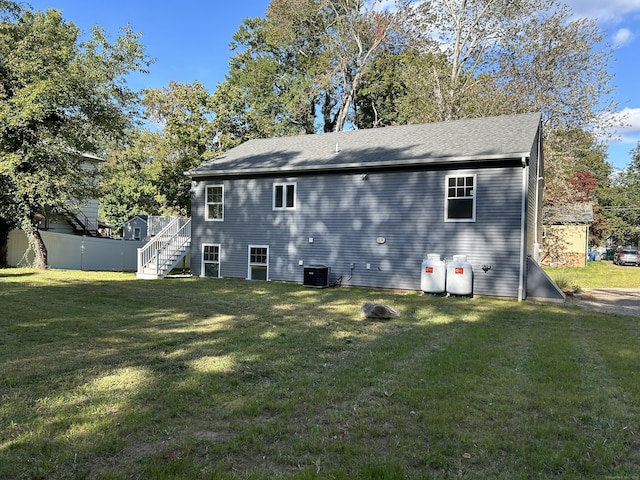 rear view of property featuring a yard and central AC