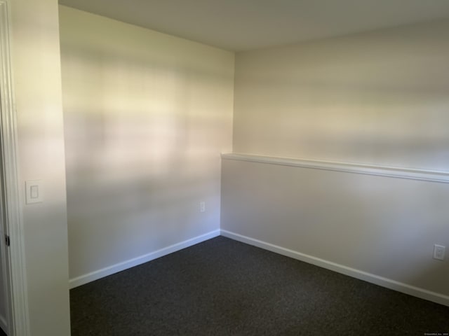 unfurnished room with dark carpet