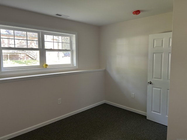 unfurnished room featuring dark colored carpet